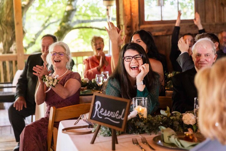 guests laugh seated at their tables in the barn wedding at pinehall at eisler farms