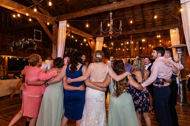 wedding guests dance together with their arms around each other, late into the night at the wedding reception at pinehall at eisler farms