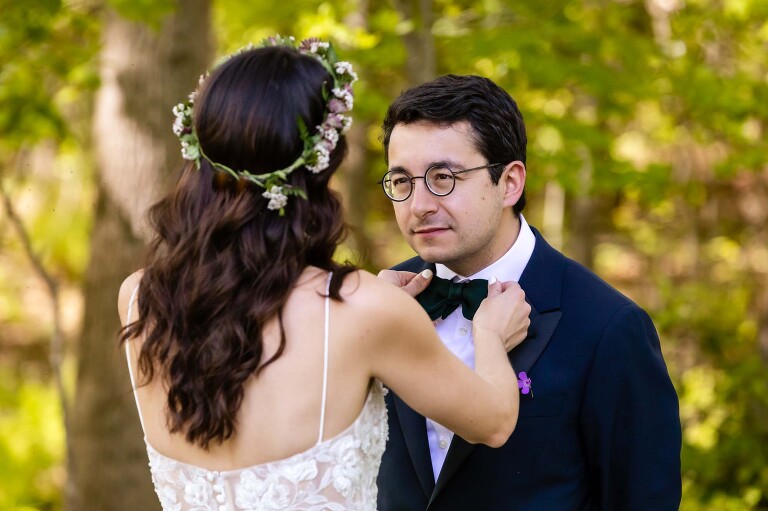 bride adjusts the groom's bow tie on their wedding day, as they see each other for the first time all dressed up in their First Look. image taken by candid wedding photographer in pittsburgh