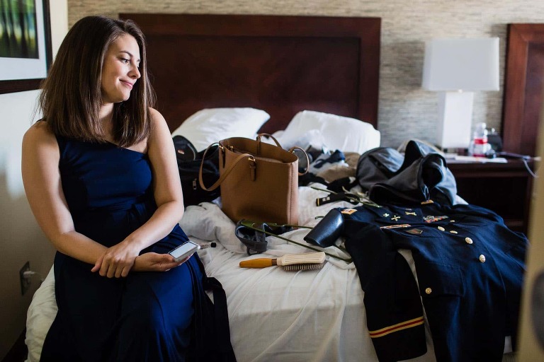 woman looks at military suit on bed, before their small wedding in pittsburgh