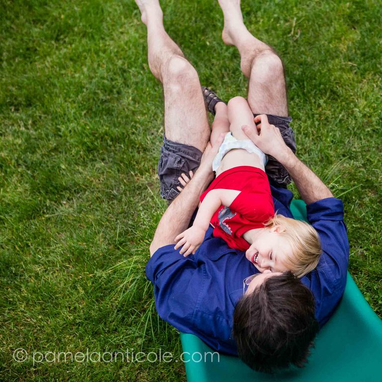 baby hugging daddy outside on slide, family joy documentary photography