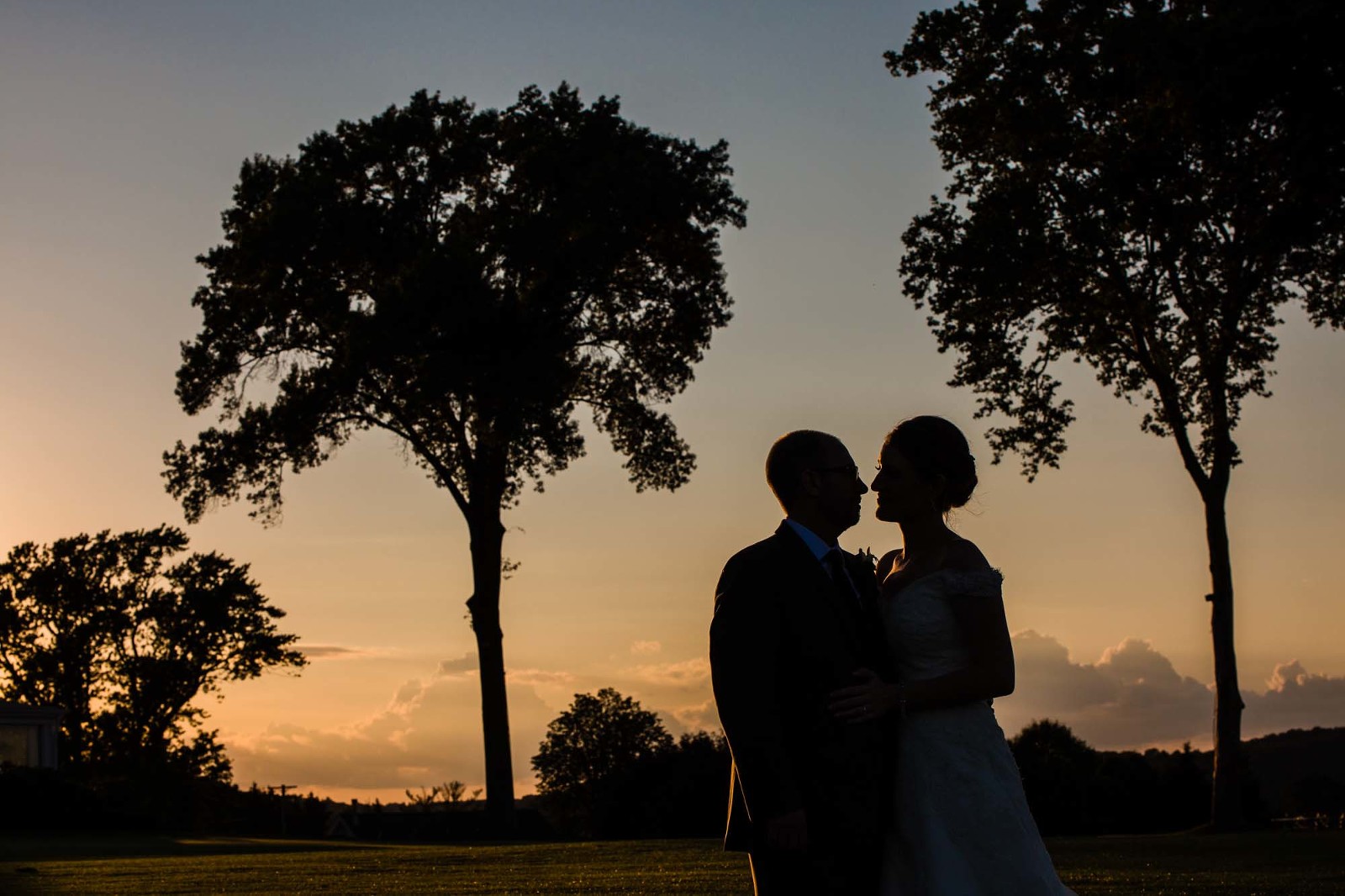 silhouette of bride and groom at sunset surrounded by trees, on oakmont country club golf course