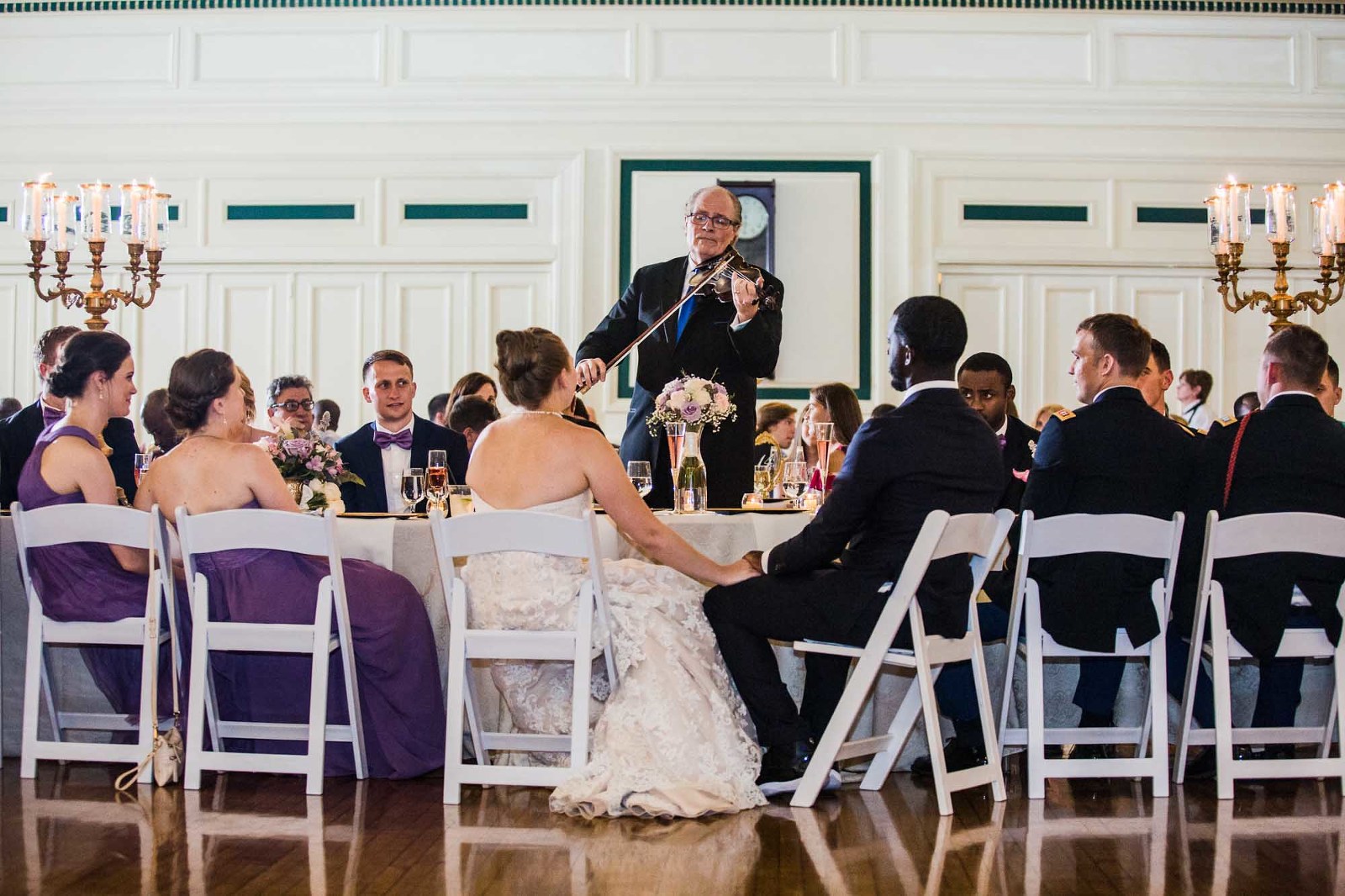 violinist serenades a bride and groom while their wedding party, bridesmaids, groomsmen, family, and friends look on at their wedding reception at the unique pittsburgh venue soldiers and sailors