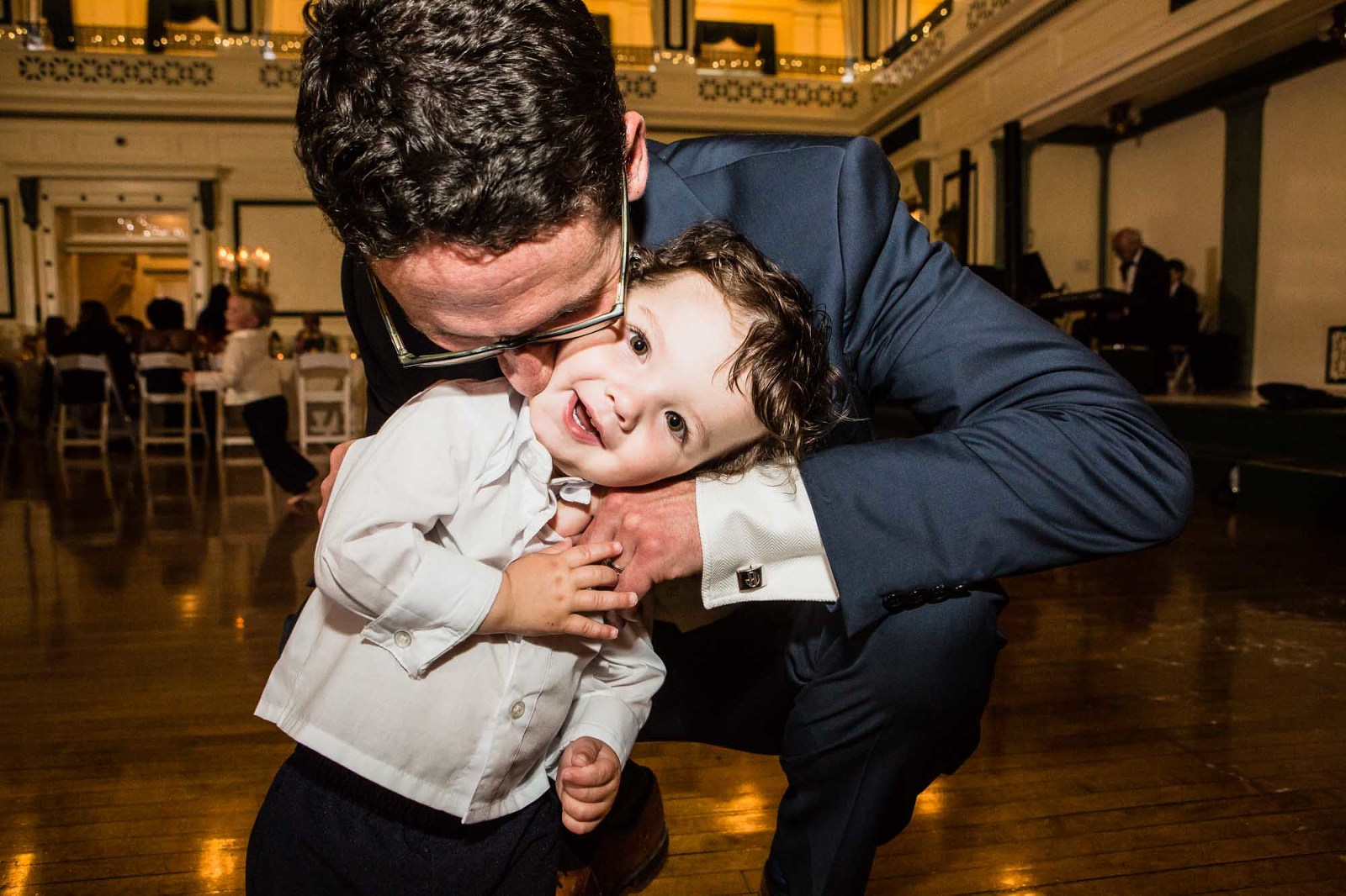 adorable photograph of a little ring bearer being hugged by his dad at his aunt's wedding reception at the unique pittsburgh wedding venue soldiers and sailors