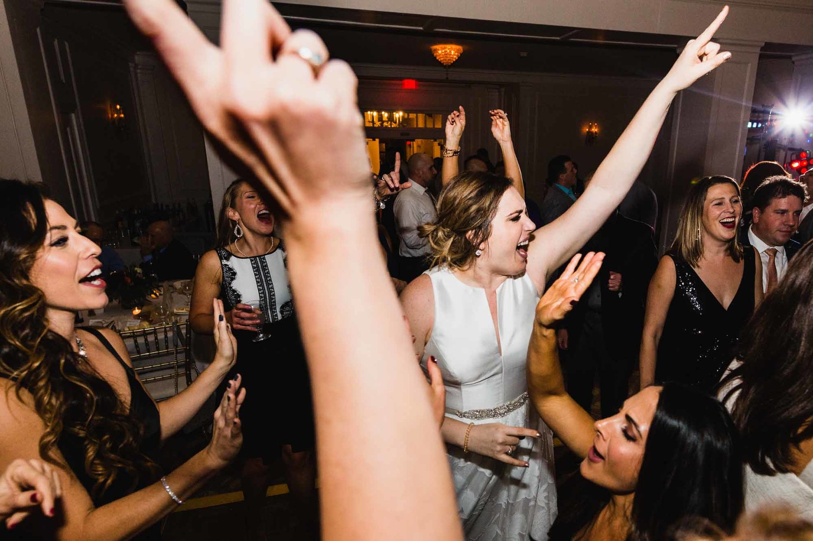 bride dances wildly with her guests, fingers in air