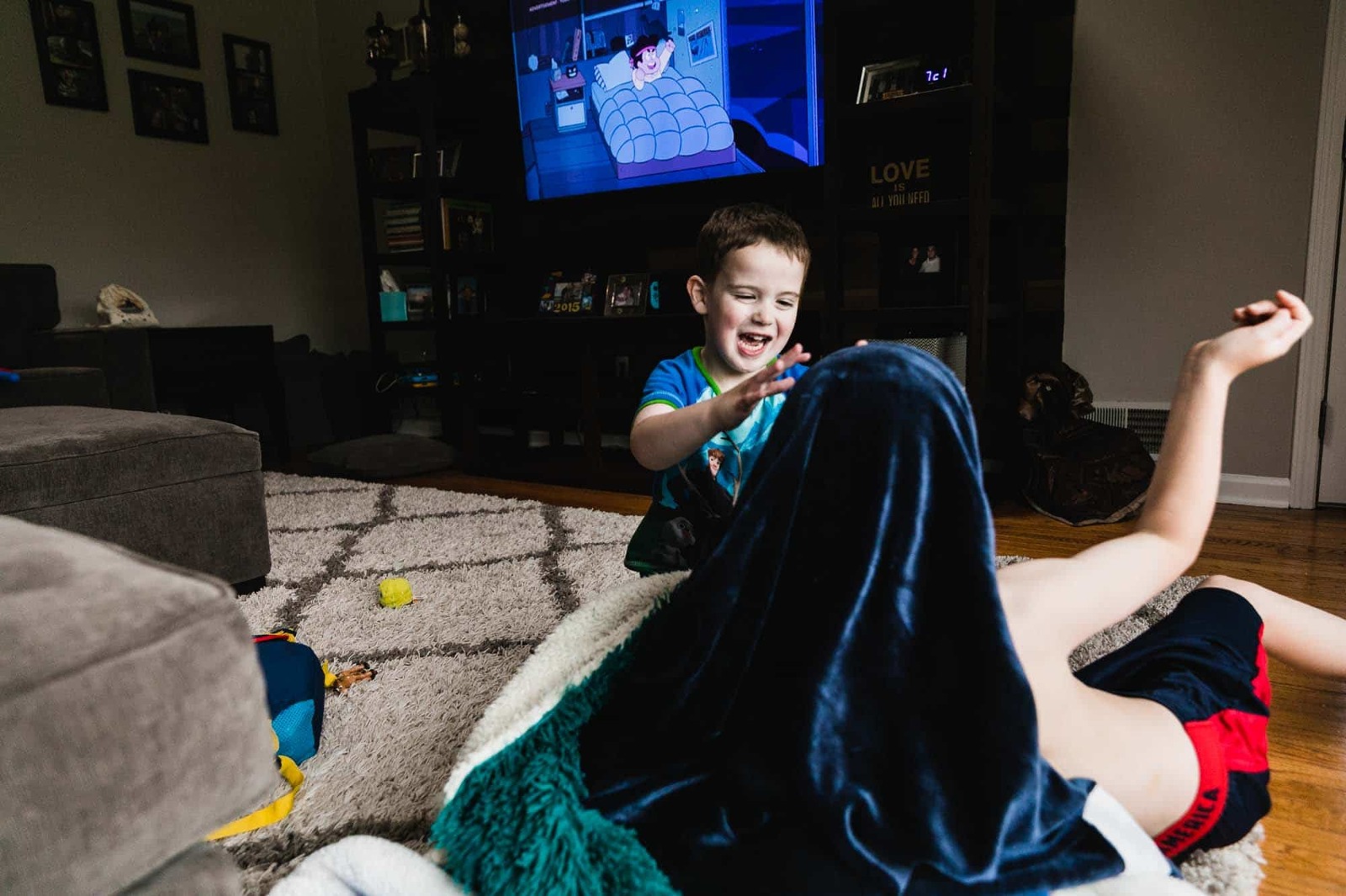 brothers wrestling with a blanket in front of the tv