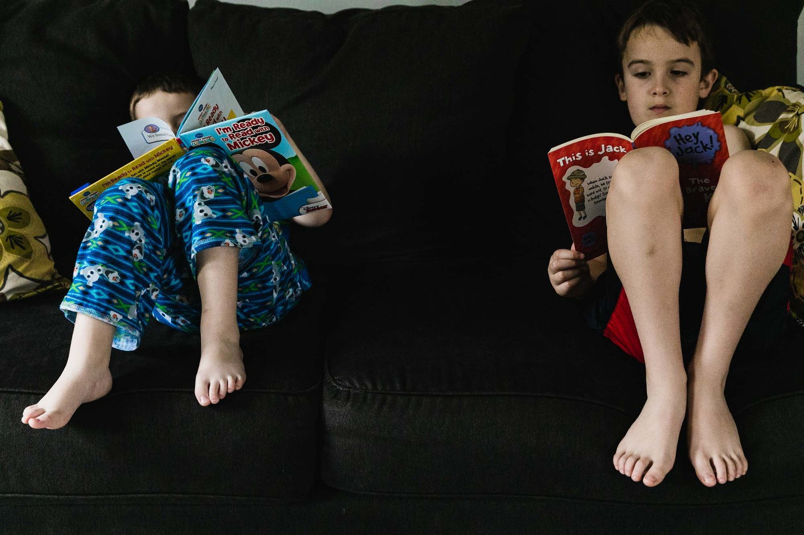 boy and his brothers reading next to each other on the couch, in pajamas
