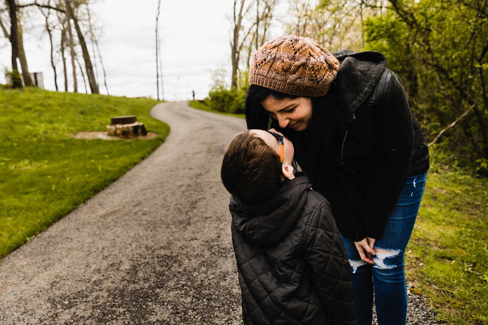 mom leans over to give smiling attention to her young boy