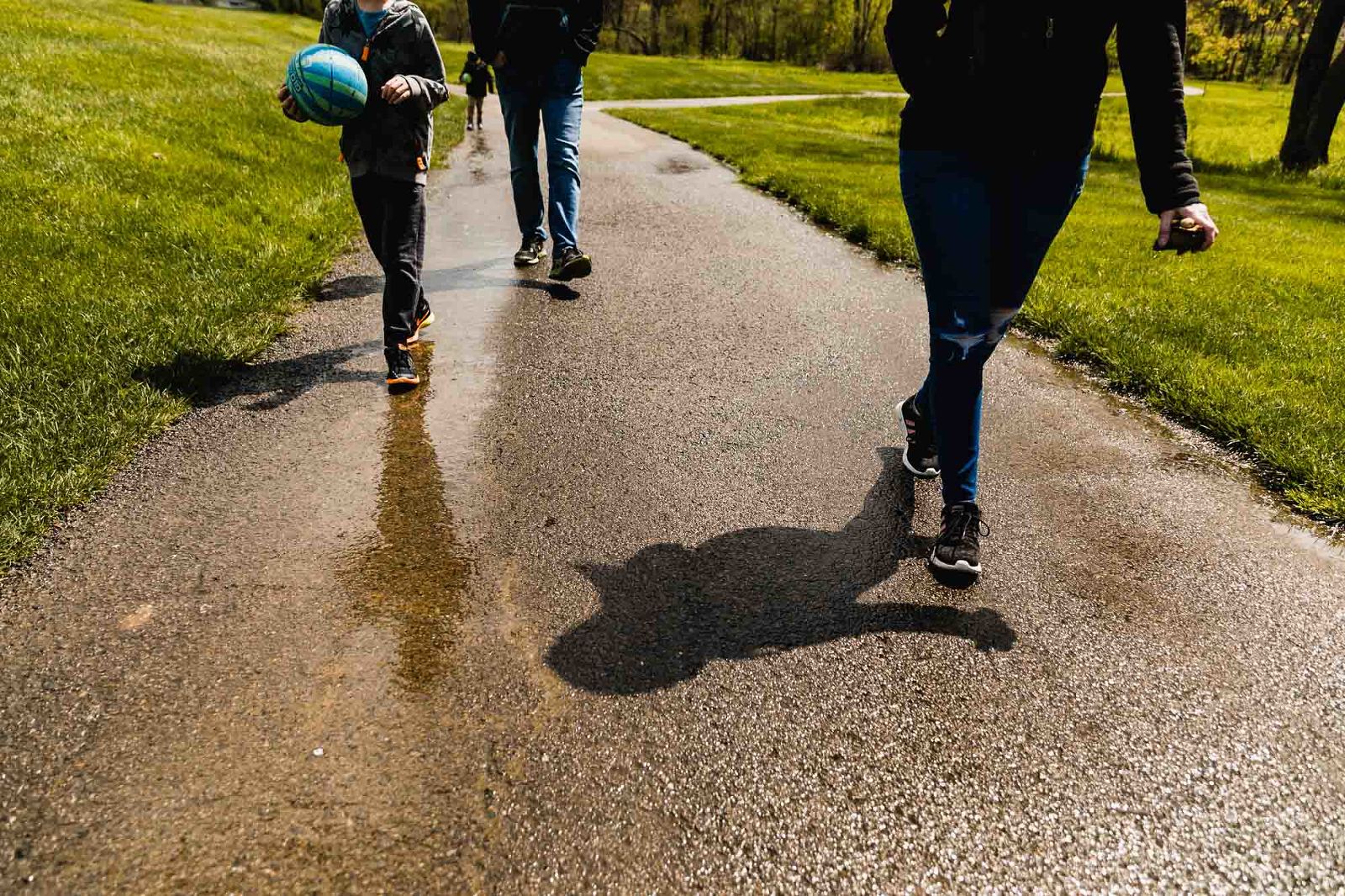 family of four walks together along a path, as photographed below their waists