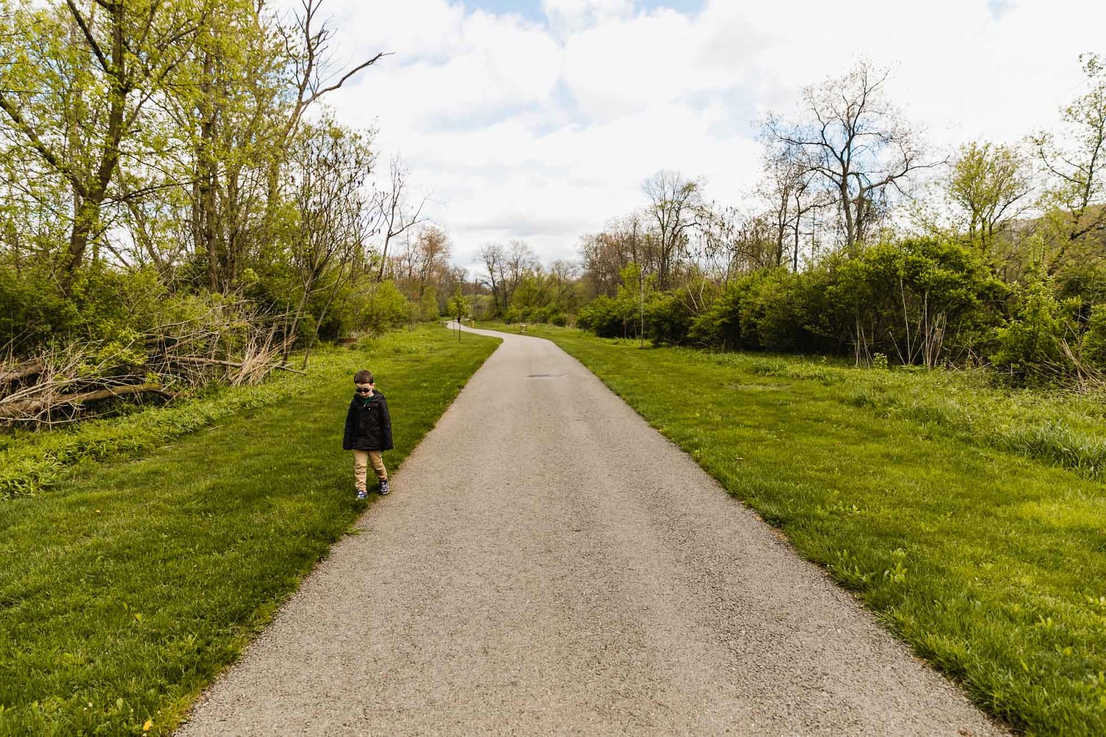 little boy walking outside the path on the grass