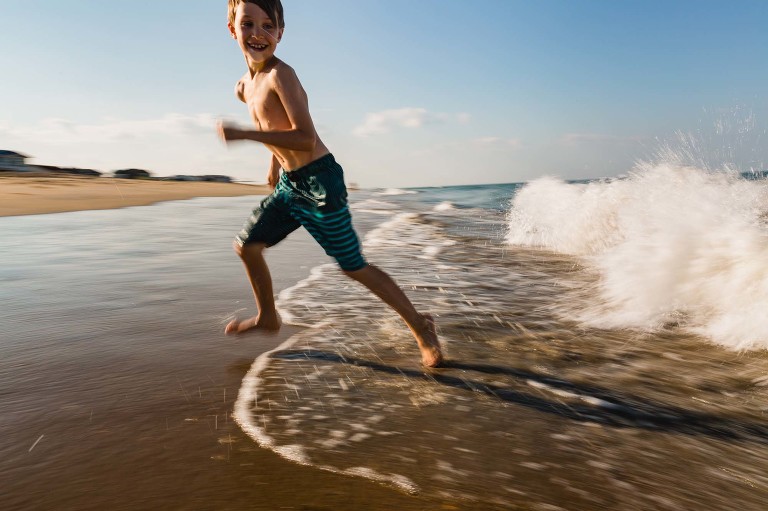 boy running away from waves at the beach