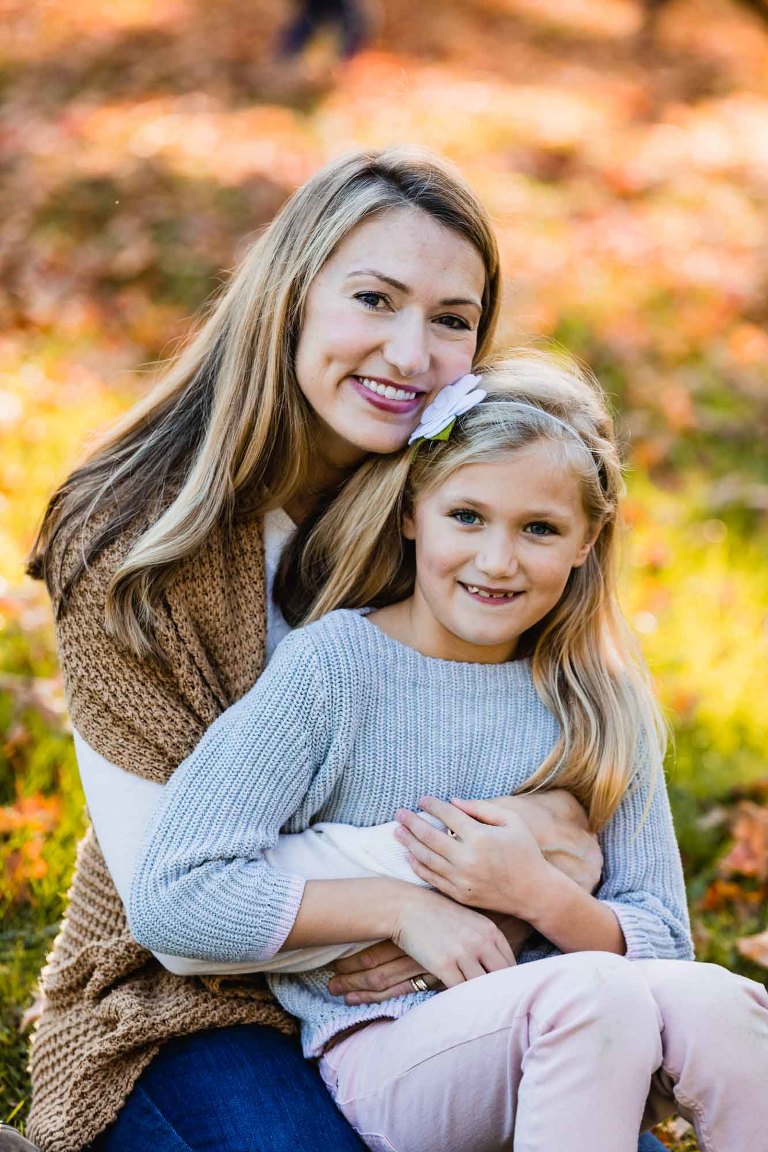 mom snuggling with her little girl outside in the spring for a photography session