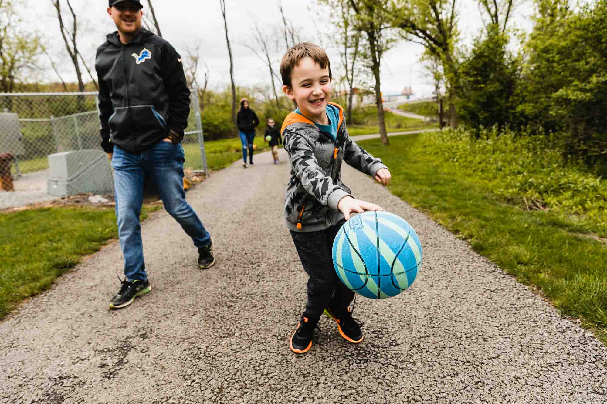 boy dribbles basketball walking with dad