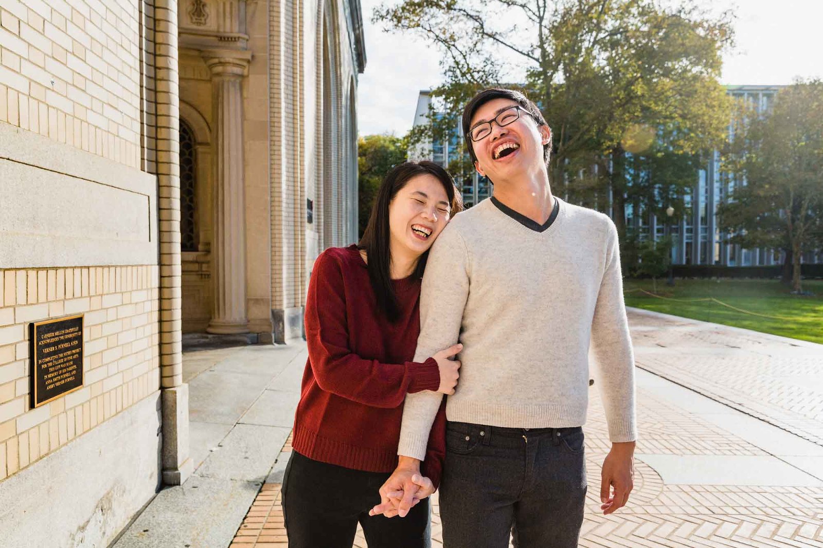 boy and girl holding hands, walking, and laughing together on carnegie mellon's campus