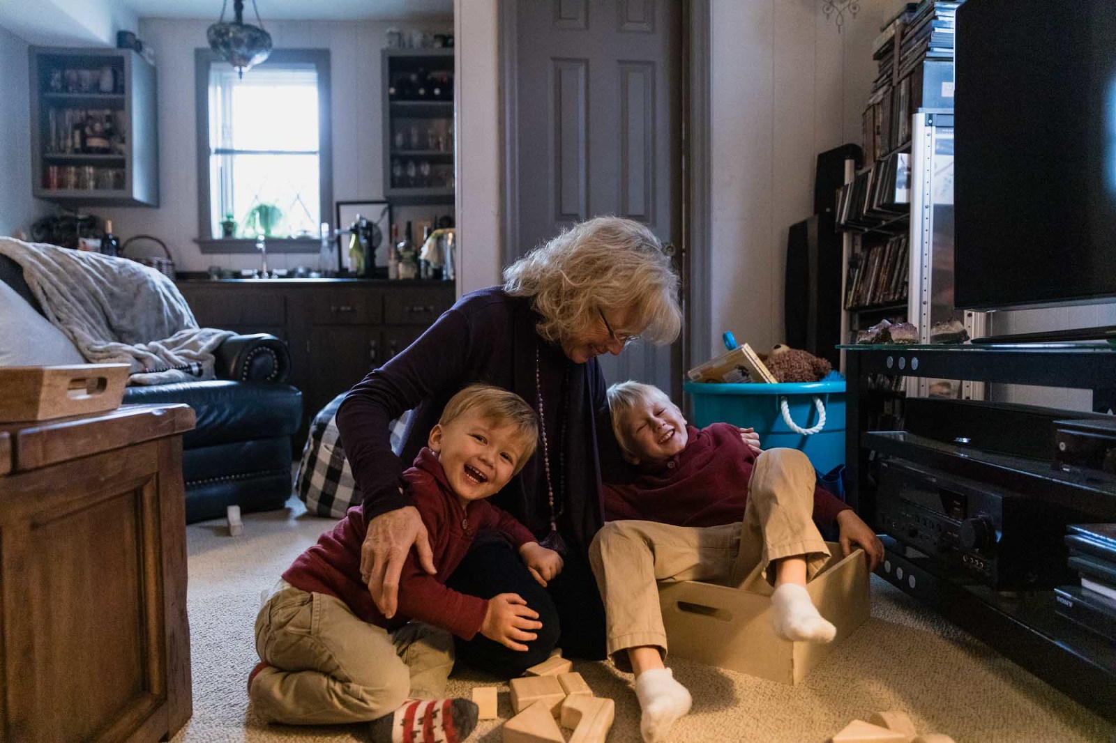 grandma wrestles with two boys on the floor of her home