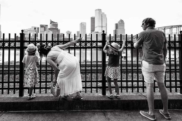 family stands in front of fence overlooking the big city of pittsburgh in the distance