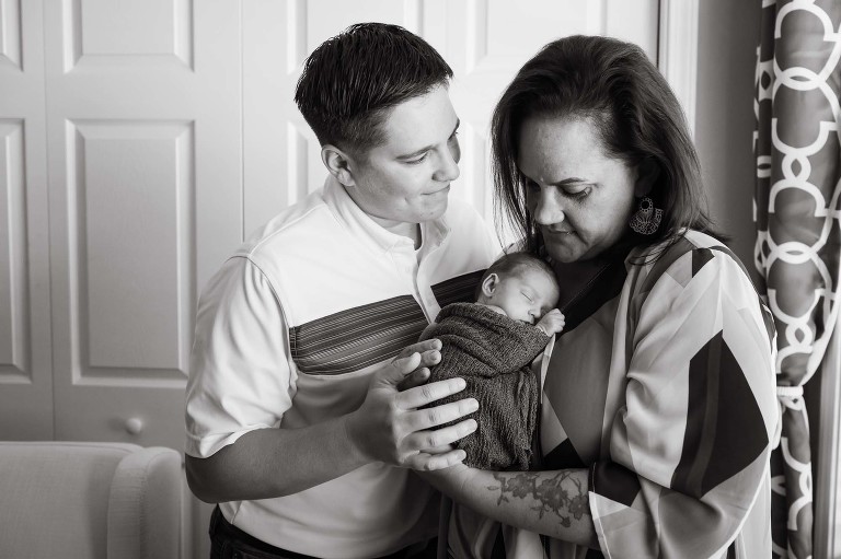 black and white photo of moms snuggling with baby girl in window light