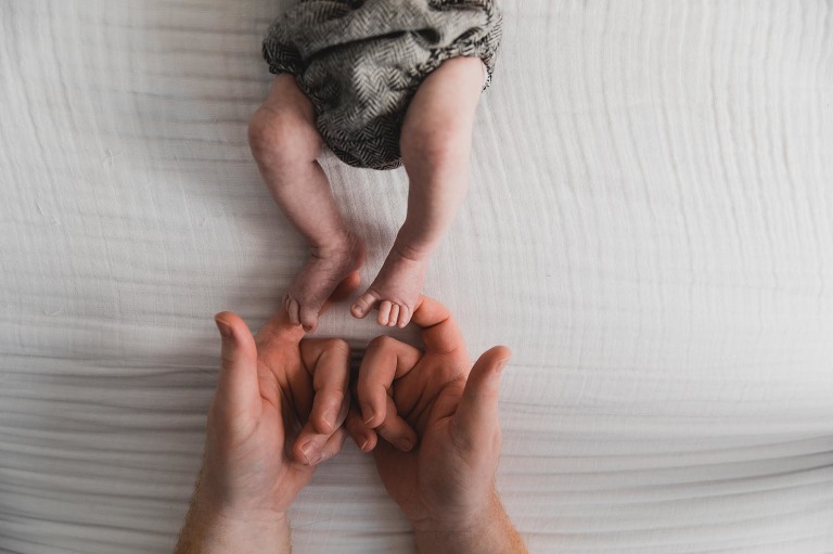 tiny newborn baby feet being touched by daddy's fingers and fitting in his hands