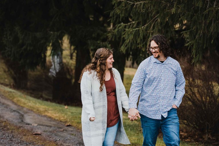young couple walk together in the winter outside along a tree lined path