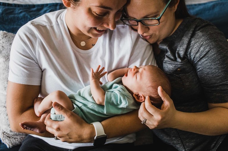 same sex female couple snuggles with their newborn baby girl