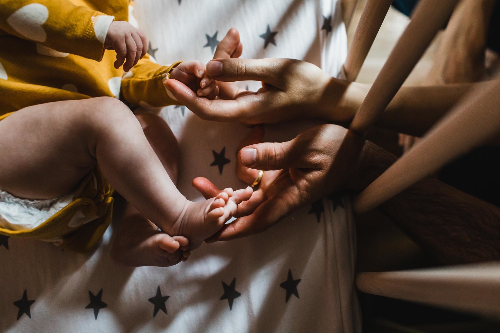 hands reaching into a baby's crib touching baby's hands and feet, taken in pittsburgh home by newborn photographer pamela anticole