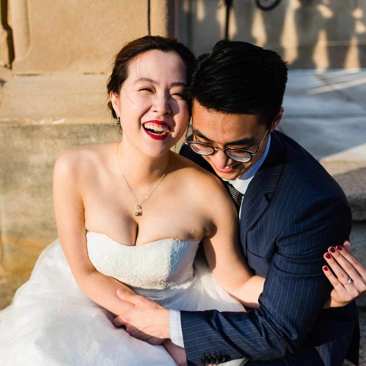 bride laughing with her whole face, while snuggling up with a man in a suit (the groom!), both of them bathed in beautiful warm sunset light