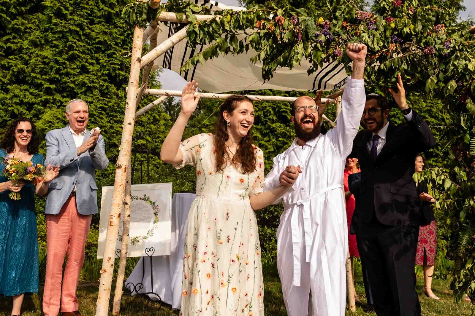 jewish bride and groom celebrate after breaking the glass under the chuppah at their wedding