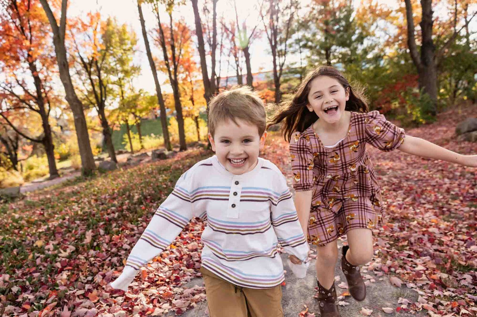 young boy and girl run laughing toward the photographer