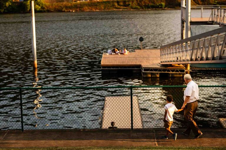 wedding guests walk along the water at the aspinwall riverfront park