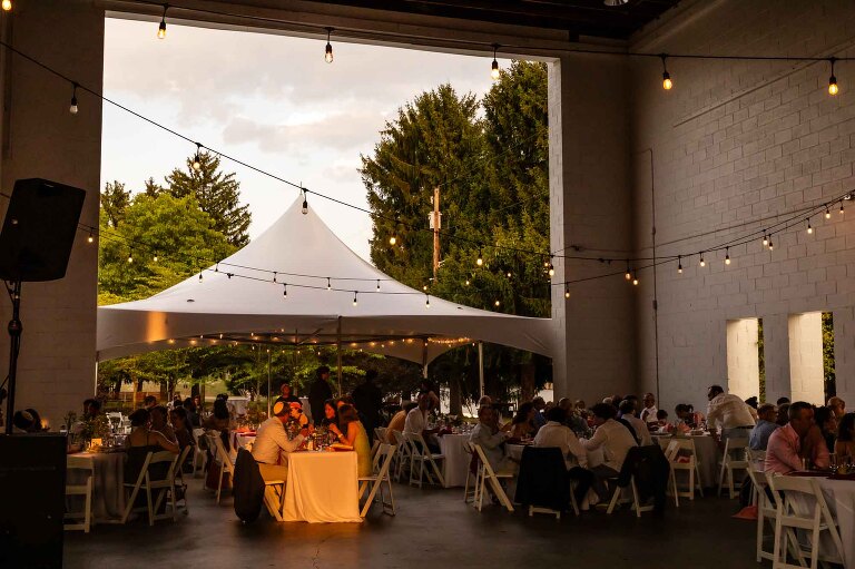 allegheny rivertrail park wedding photos | sunset picture of outdoor wedding venue with covered patio, with guests seated and eating