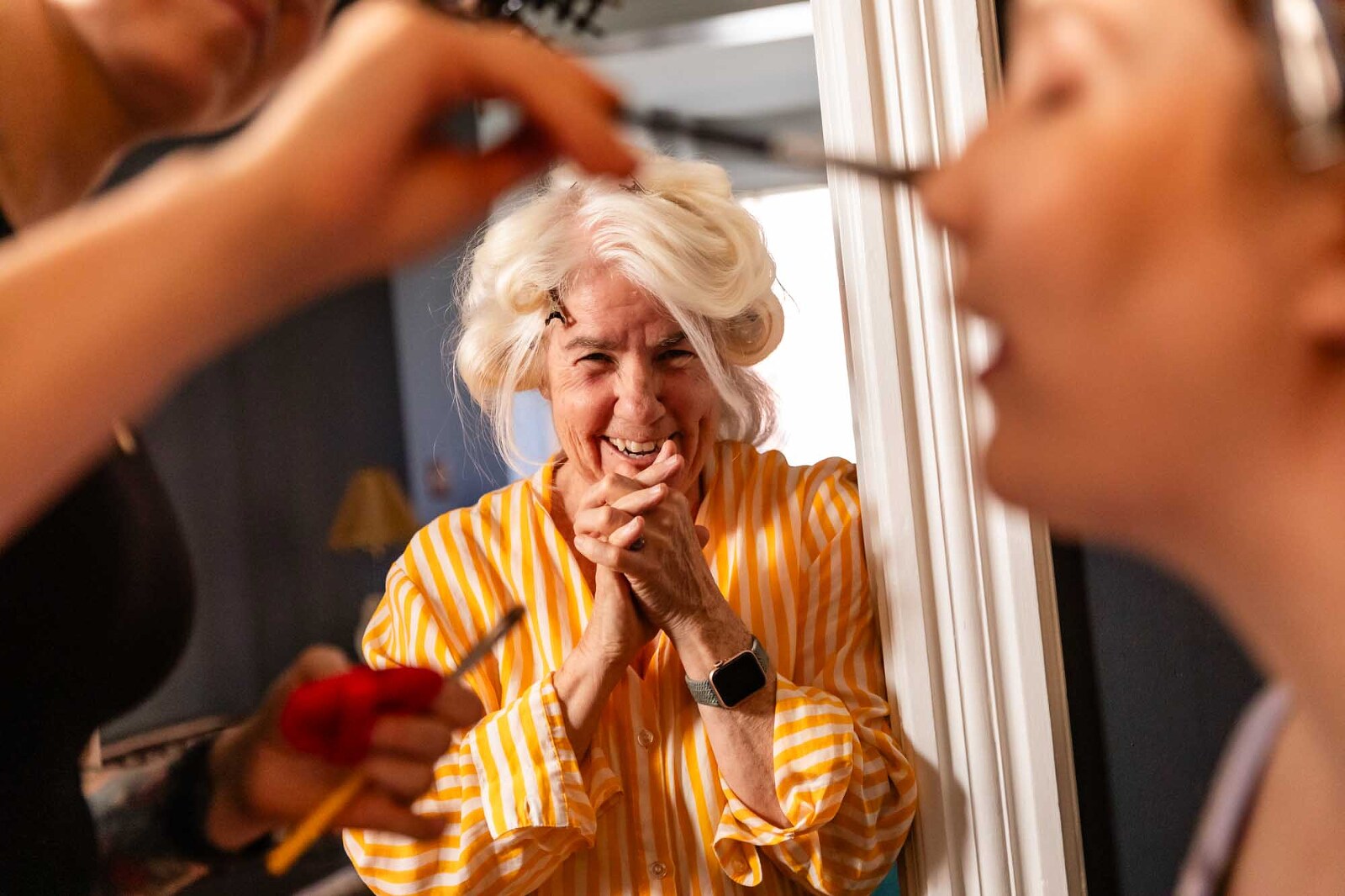 mother of the bride watches gleefully as her daughter gets her makeup put on on her wedding day. picture taken by pittsburgh wedding photographer pamela anticole