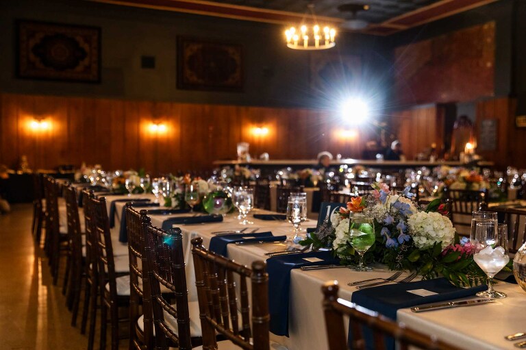 The indoor ballroom is shown in WBU Event Venue wedding photos, with flowers and place settings and a warm chandelier light