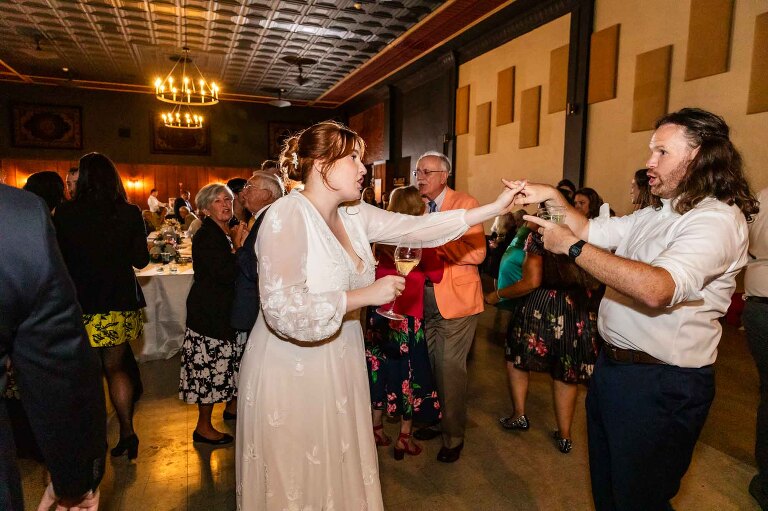 bride and groom dance together at a wedding reception, in their WBU Event Venue wedding photos. beautiful tin ceiling is shown off!
