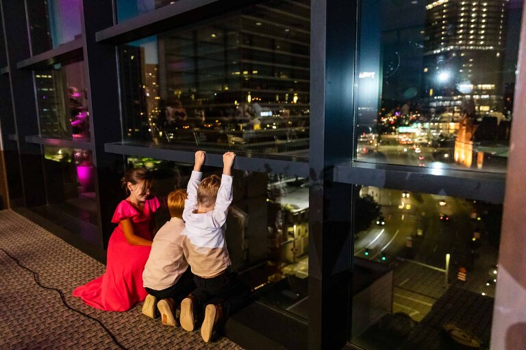 kids looking at pittsburgh skyline at duquesne power center ballroom, hanging from the windows late at night.