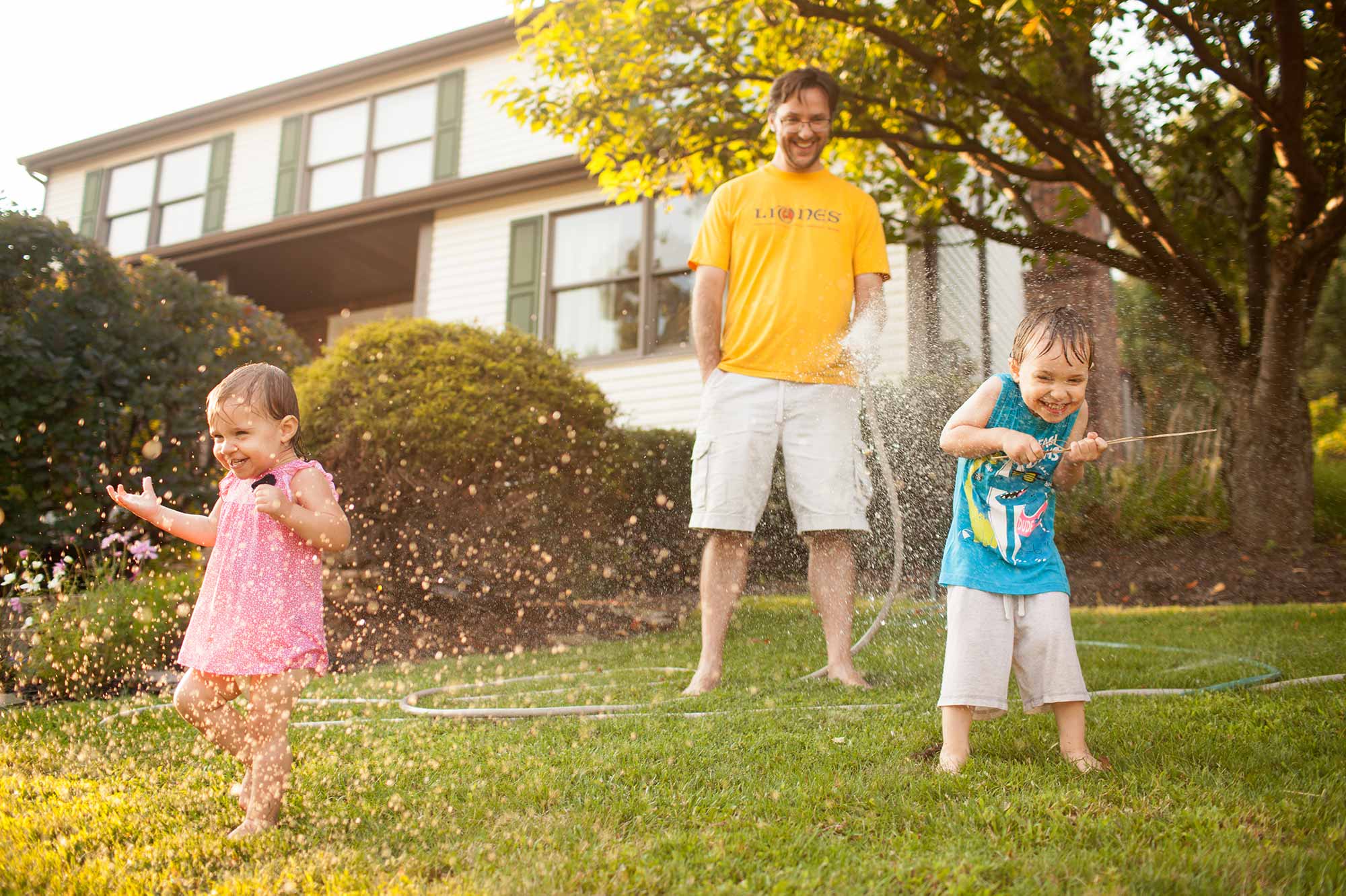 newborn photographer doesn't just capture newborn pics, but includes siblings, too! dad spraying kids with water