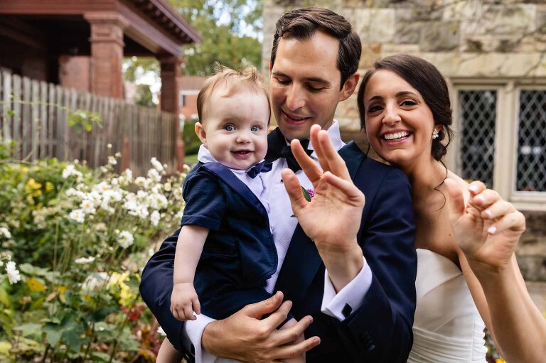 mom and dad wave with baby on their wedding day at first unitarian church in shadyside pittsburgh