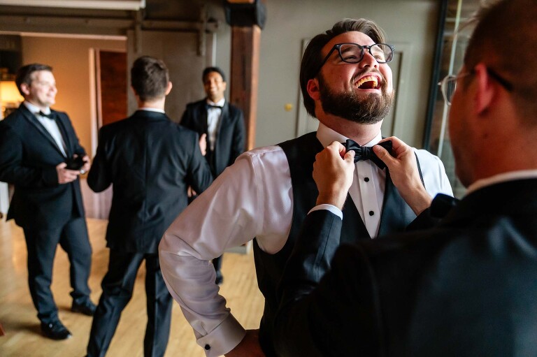 groom laughs as he gets ready for his heinz history center wedding, in the separate bridal spaces on site at this unique pittsburgh wedding venue