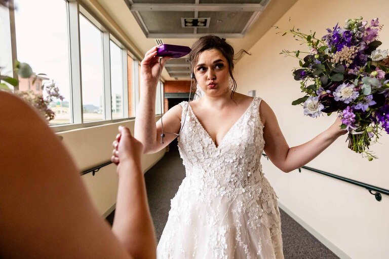 bride is very hot on her wedding day and fans herself to stay cool, in a hallway at the heinz history center for their wedding.