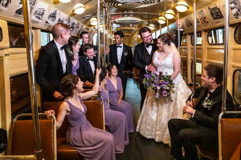 bride and groom are surrounded by their bridal party in the classic trolley in the grand hall, at their heinz history center wedding. pictures by documentary wedding photographer pamela anticole