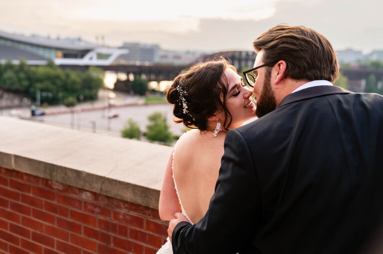 bride and groom kiss at sunset on the balcony overlooking the city of pittsburgh, at the heinz history center.