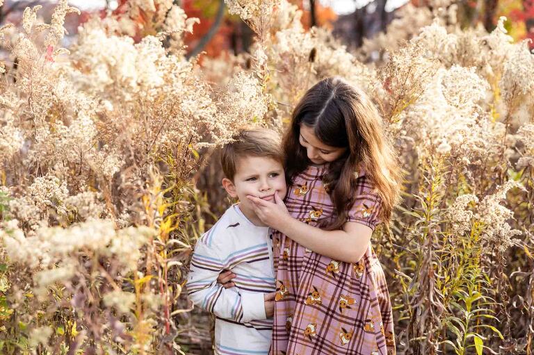 young kids standing in tall grasses acting silly in a candid portrait