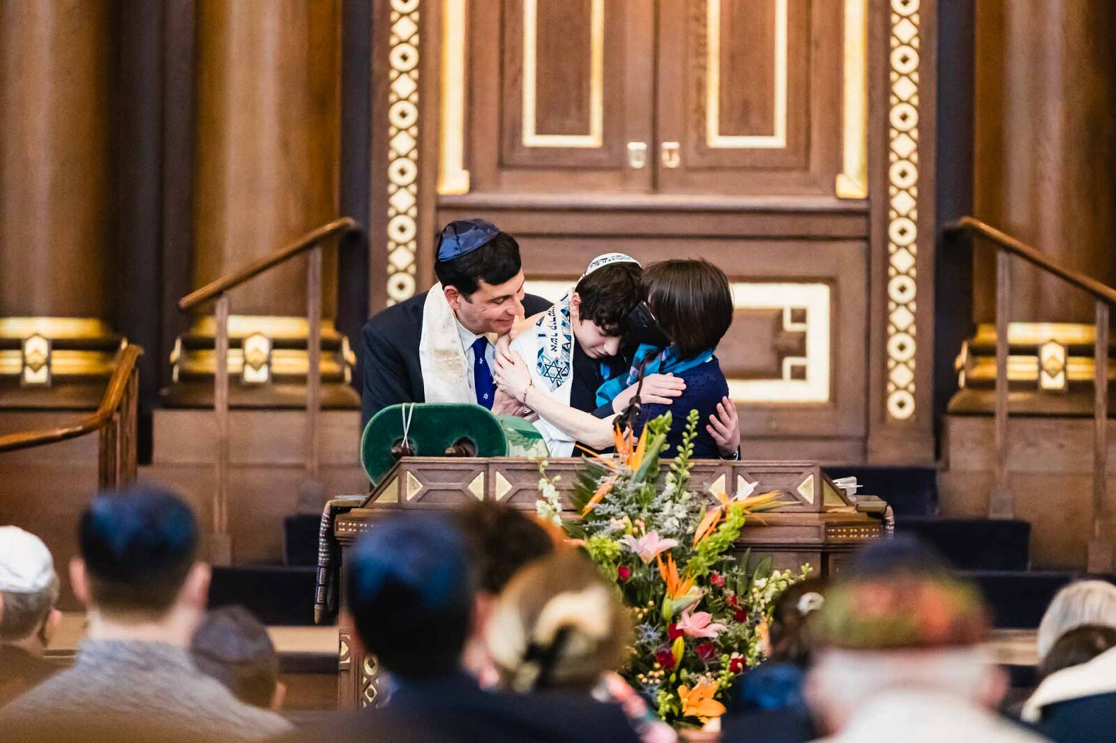 in bar mitzvah at rodef shalom, boy hugs his parents during the service
