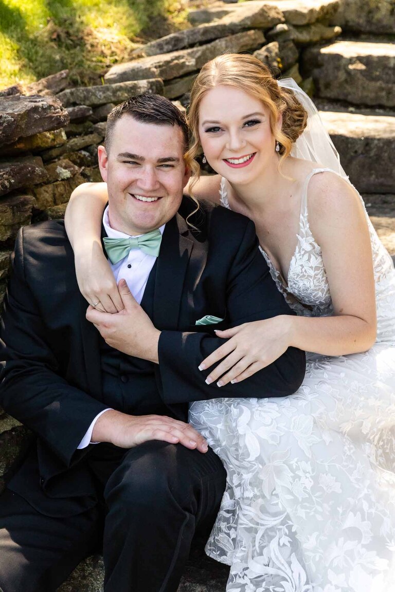 bride and groom sitting together on stone steps, posing for a portrait at their wedding at pinehall at eisler farms