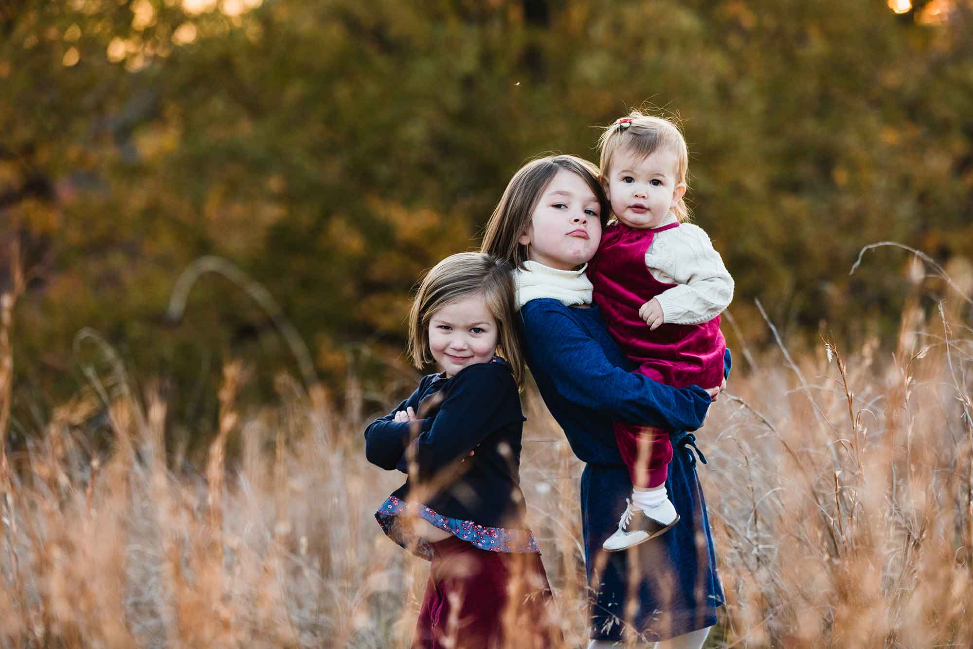 girls ham it up for the camera, standing in a field being silly for their photography mini session at north park